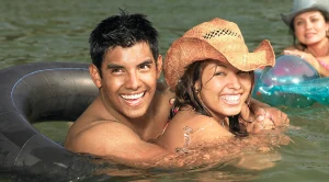 A couple swimming together in the water, smiling and having fun.