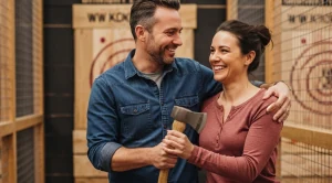 A couple holding an ax, on an axe throwing activity.