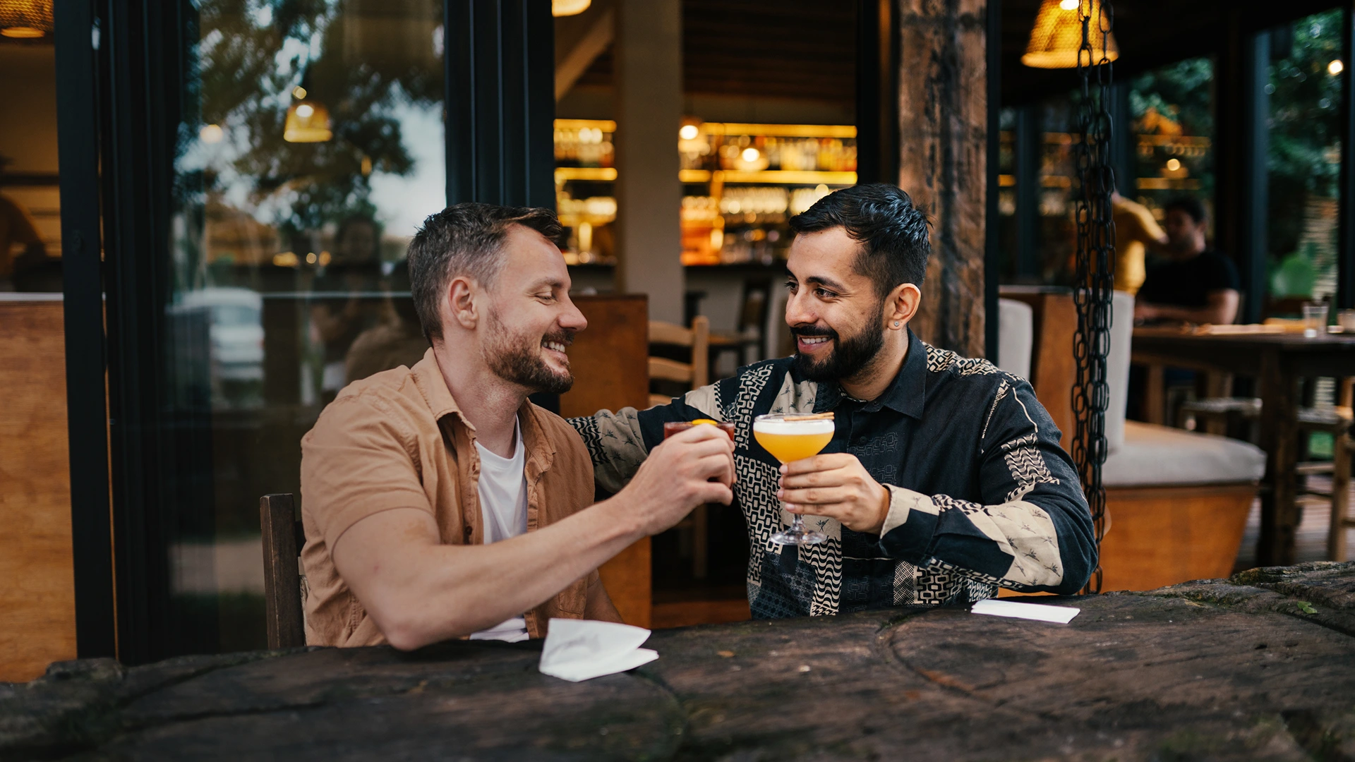 A gay couple enjoying cocktails at an outdoor bar in Houston.