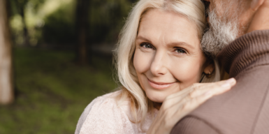A woman leaning on a man's shoulder smiles at the camera as a symbol of how eharmony works