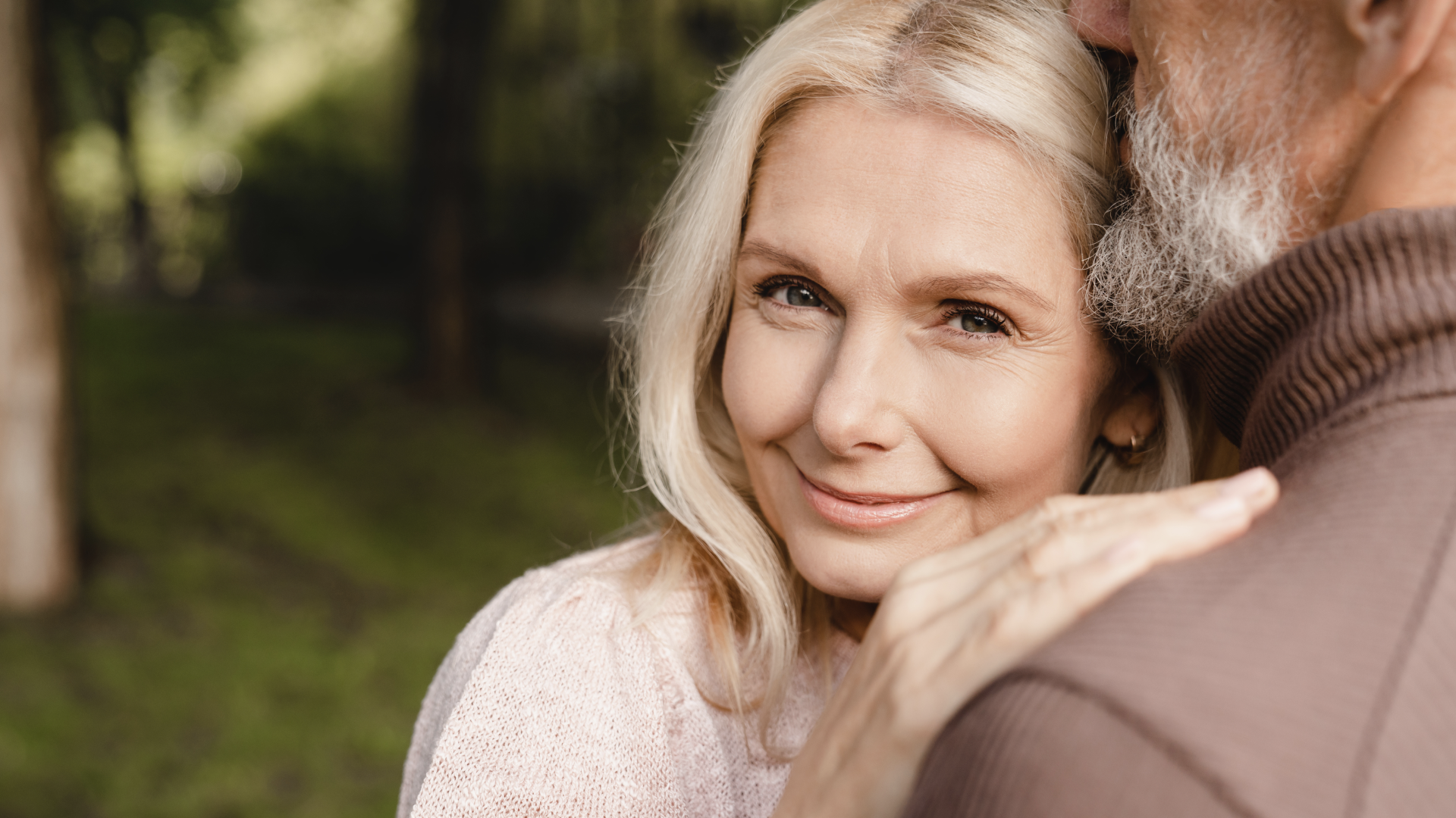 A woman leaning on a man's shoulder smiles at the camera as a symbol of how eharmony works