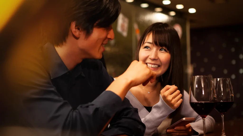 Asian couple in a bar looking at each other and having a good time.