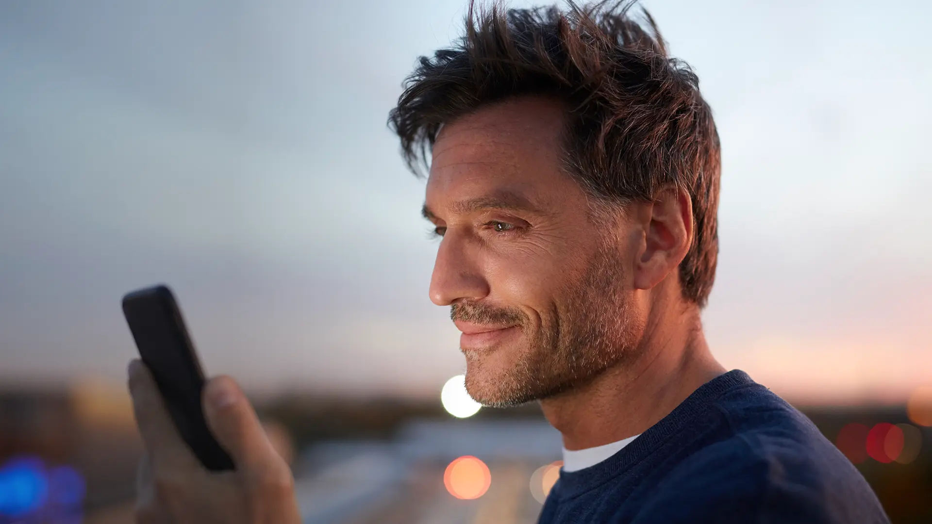 Man on his phone in front of a sunset